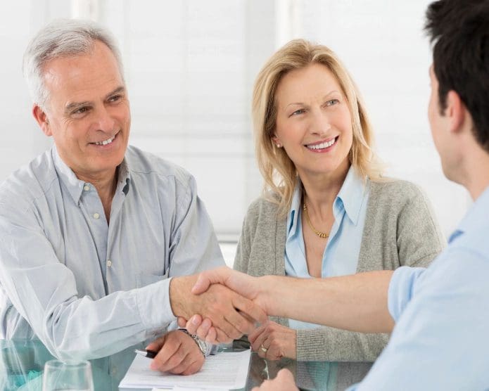 A man and woman shaking hands over a table.