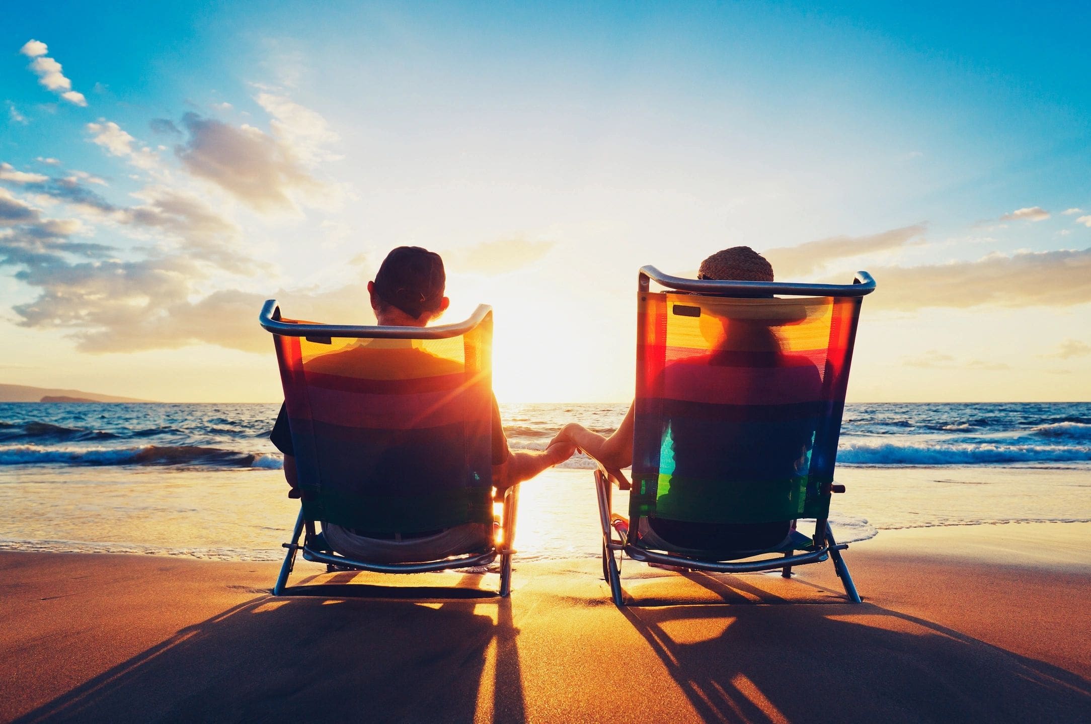 Two people sitting in lawn chairs on the beach